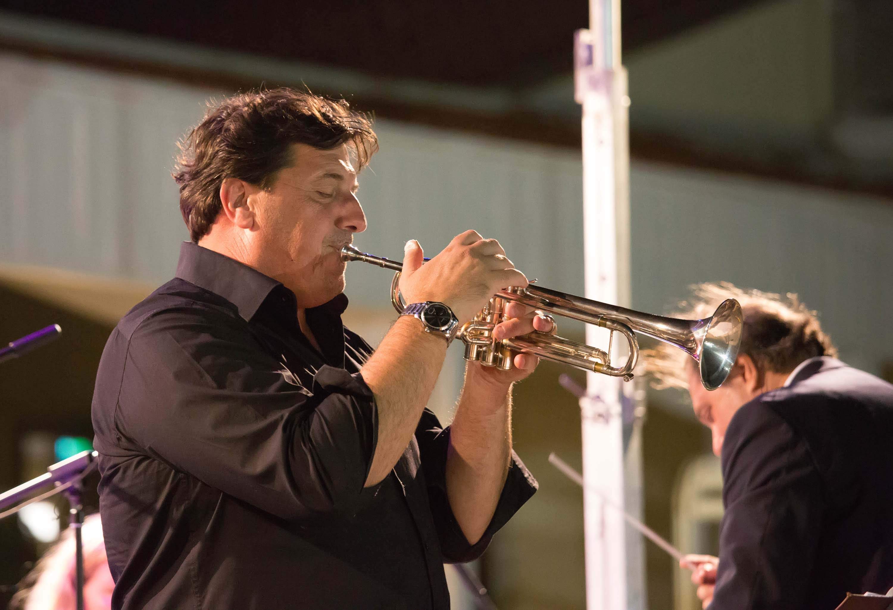 Trumpet soloist performing at an evening concert, with the conductor behind him